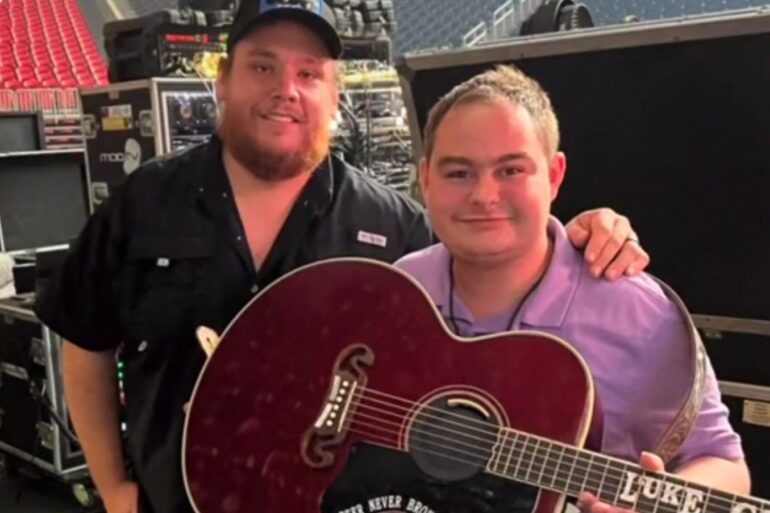 Luke Combs holding a guitar next to a man holding a guitar