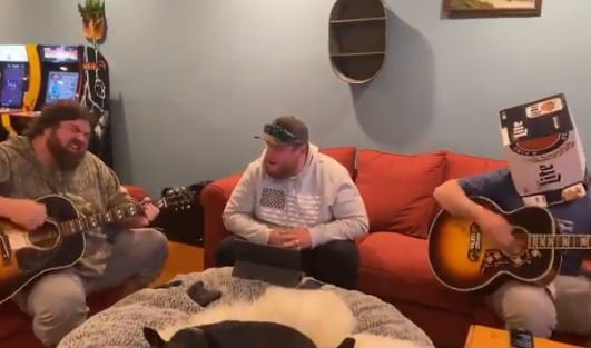 A man playing a guitar next to another man playing a guitar
