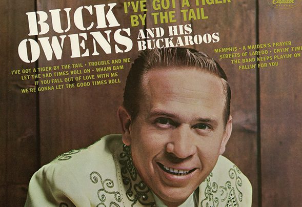 Buck Owens smiling in front of a magazine