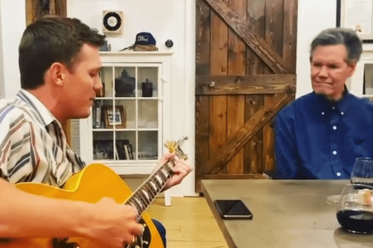 A man playing a guitar next to another man playing a guitar