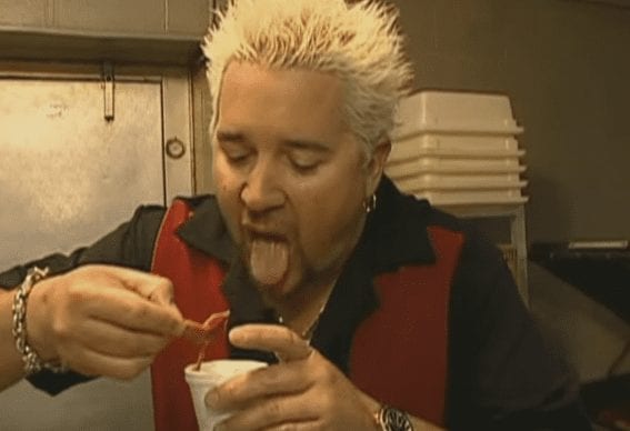 Guy Fieri with the mouth open holding a cup of coffee