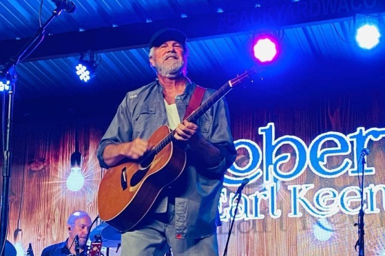 Robert Earl Keen playing a guitar on a stage