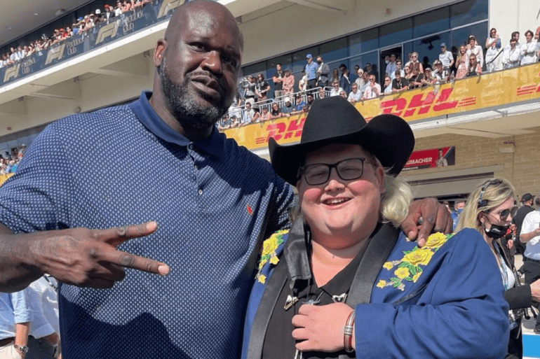 Shaquille O'Neal and Joshua Ray Walker posing for a picture in a stadium with a crowd of people