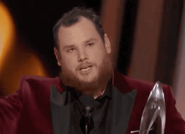Luke Combs speaking into a microphone