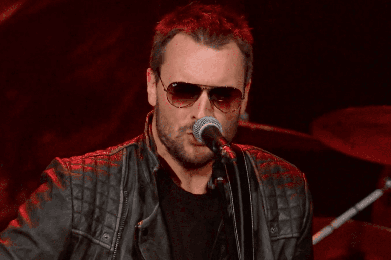 Eric Church with red hair and sunglasses singing into a microphone
