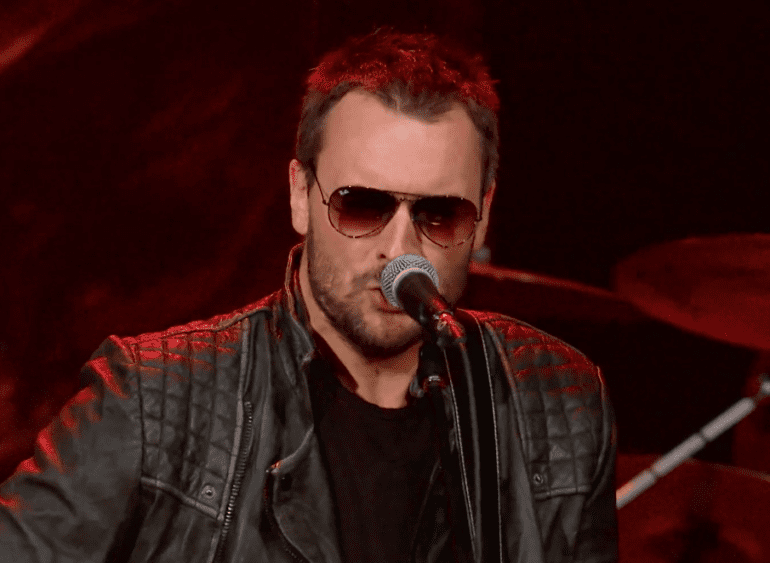 Eric Church with red hair and sunglasses singing into a microphone