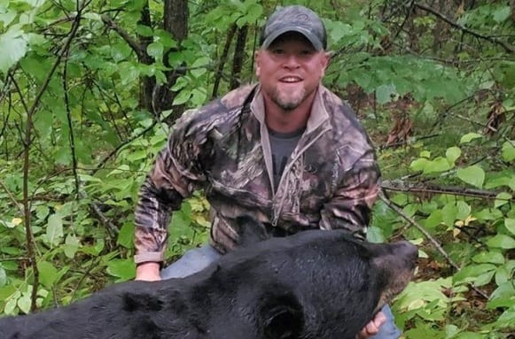 A man in camouflage with a black animal
