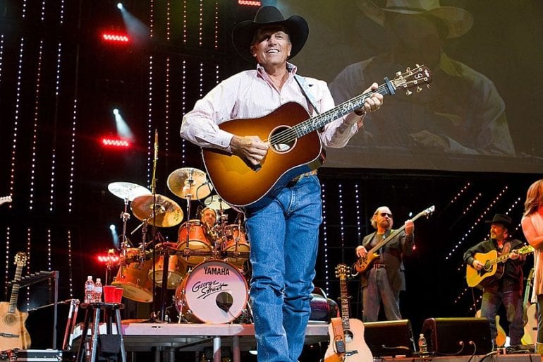George Strait playing a guitar on a stage