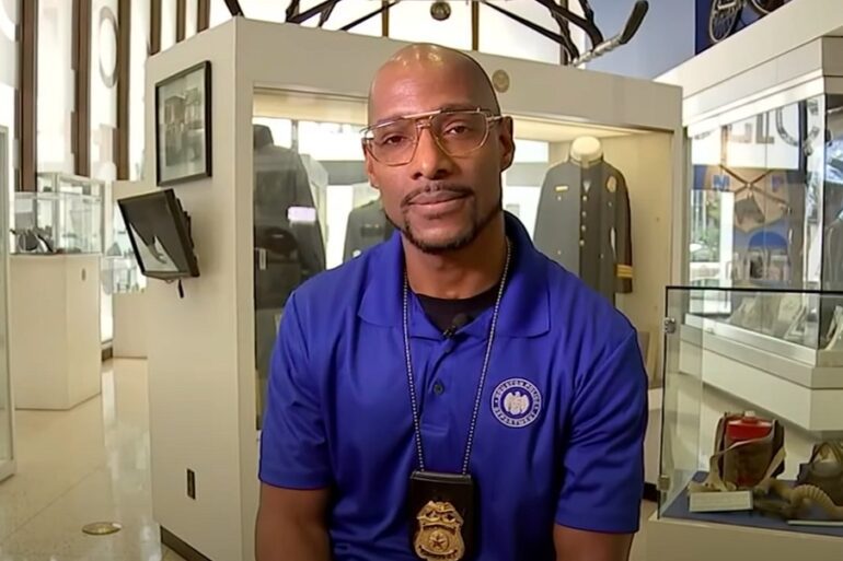 A man wearing a blue shirt and a necklace