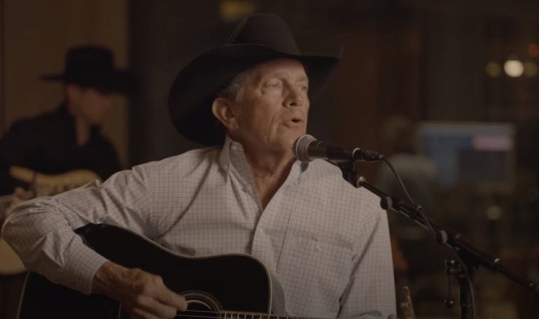 George Strait wearing a hat and sitting in front of a microphone