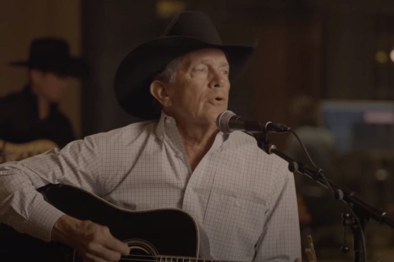 George Strait wearing a hat and sitting in front of a microphone