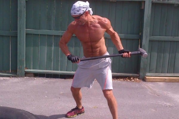 A shirtless man holding a tennis racket