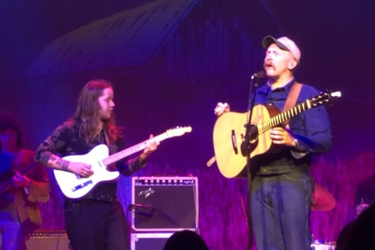 A man playing a guitar and a woman playing guitar on a stage