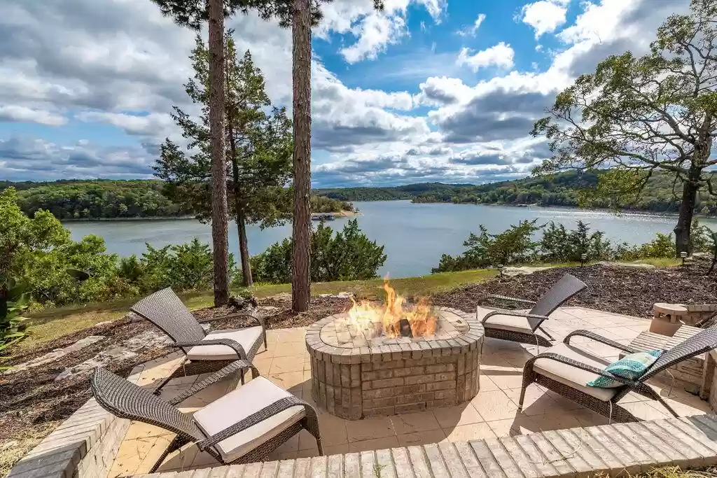 A patio with a fire pit and a view of a lake