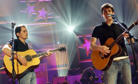 A couple of men playing guitars on a stage