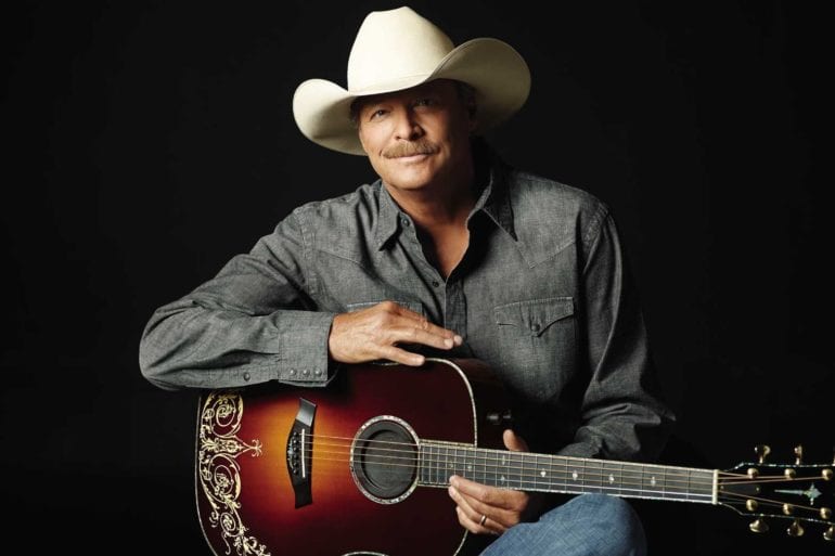 Alan Jackson wearing a cowboy hat and holding a guitar
